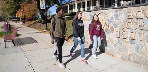 Three students walking together on the quad in fall